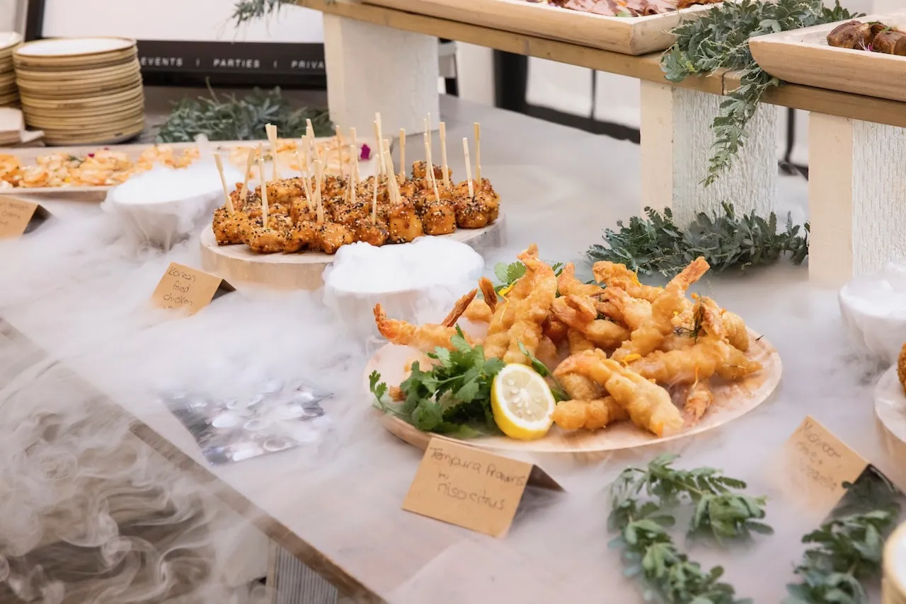 Photo of table with hot canapes on plates with dry ice fog for effect