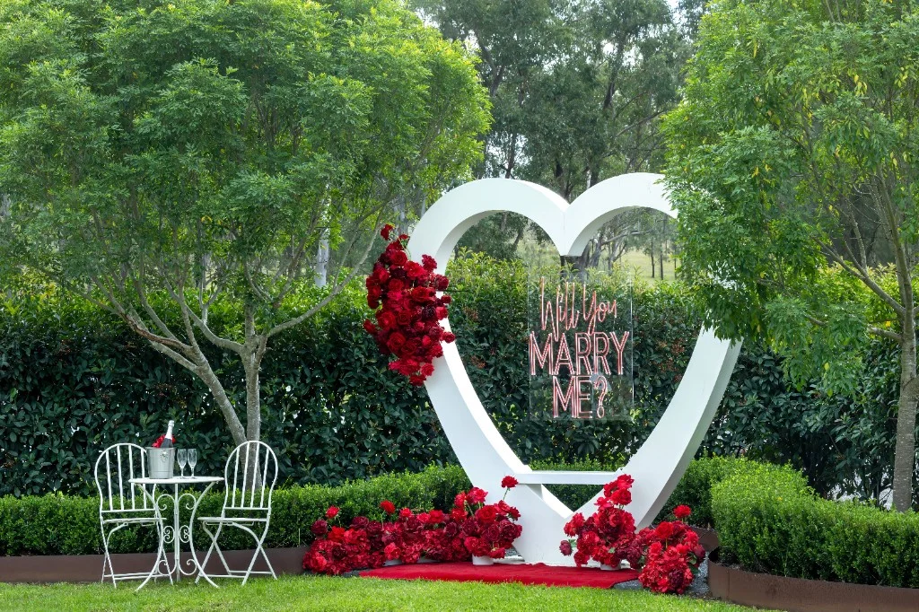 Full proposal setup with heart arch, red carpet, and sparkling wine in the White Barn garden
